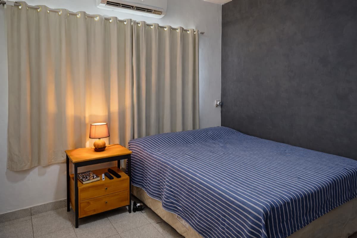 quarto com cama posta e mesa de cabeceira